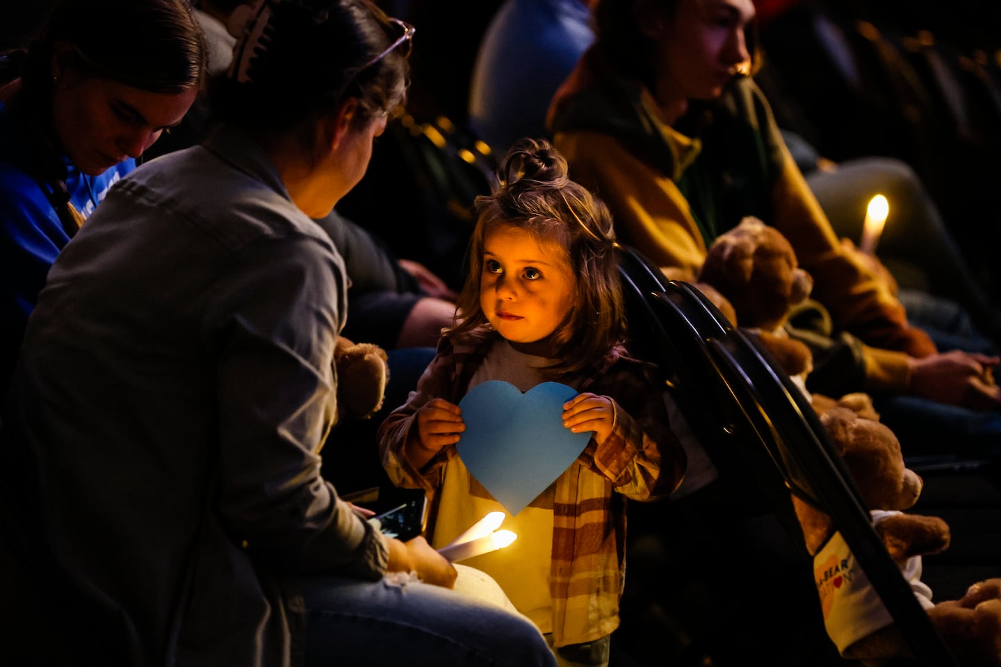 A young girl held a blue heart, symbolizing Lewiston's strength, during a memorial service marking one year since the mass shooting that killed 18 people in the Maine city on Oct. 25.