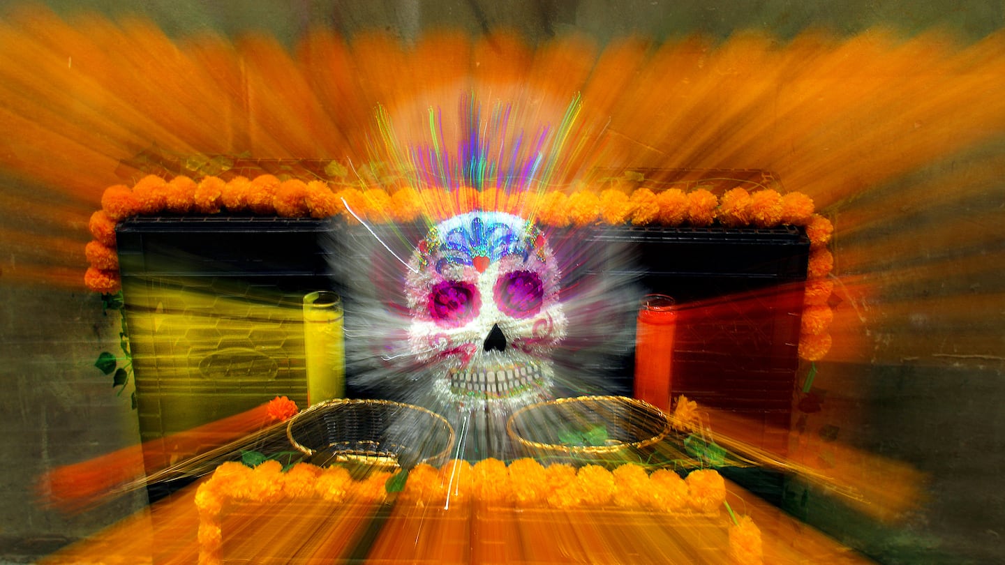 Volunteers decorated altars inside the ICA Watershed for a Day of the Dead exhibition.   A skull mask decorating an altar was photographed while lens was zoomed during 1 second exposure.