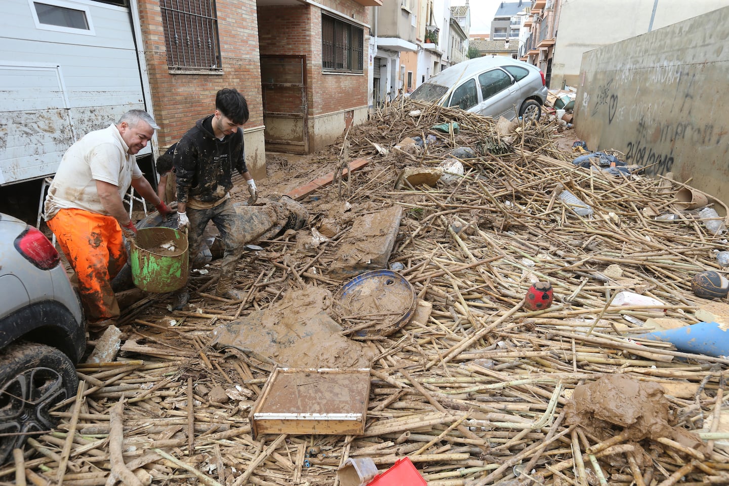 Two men carry a bucket of mud after floods in Paiporta, near Valencia, Spain, on Nov. 3.