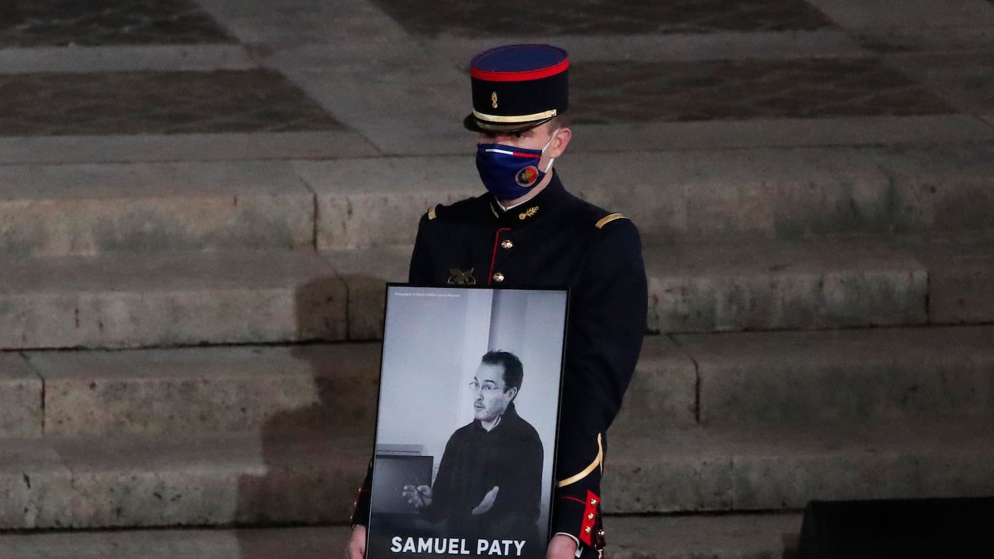 A Republican Guard holds a portrait of Samuel Paty in the courtyard of the Sorbonne university during a national memorial event, Wednesday, Oct. 21, 2020 in Paris.