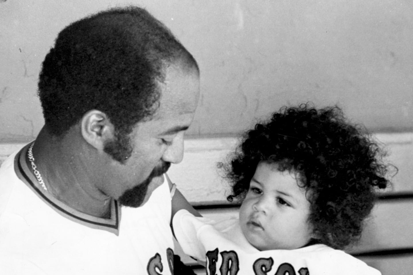 Luis Tiant holds his son, Dan, in the Red Sox dugout in 1975.