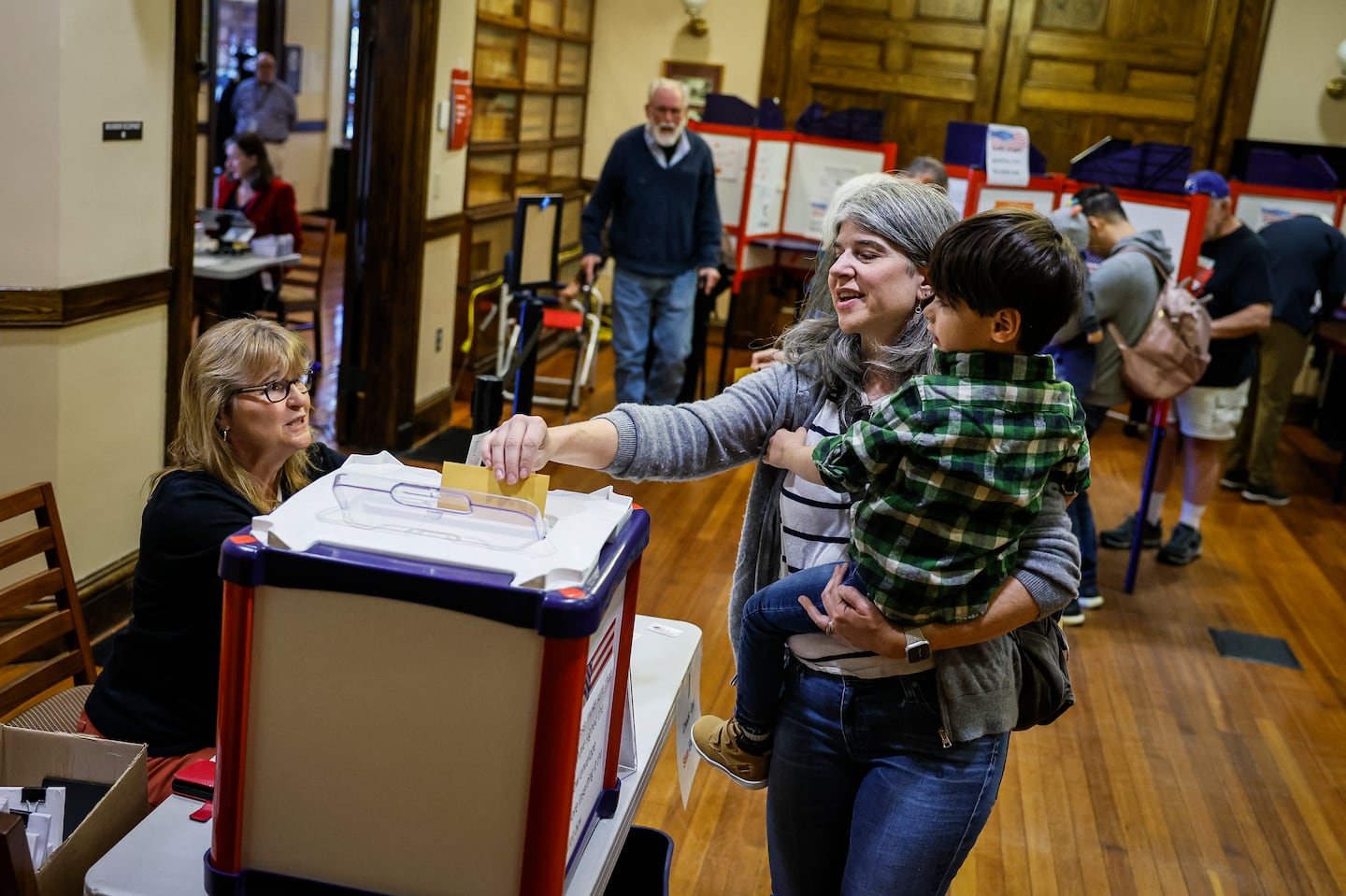 Brooke Glass cast her ballot while holding her 4-year-old son Asher on Oct. 19 during early voting at Needham Town Hall for the Nov. 5 general election.