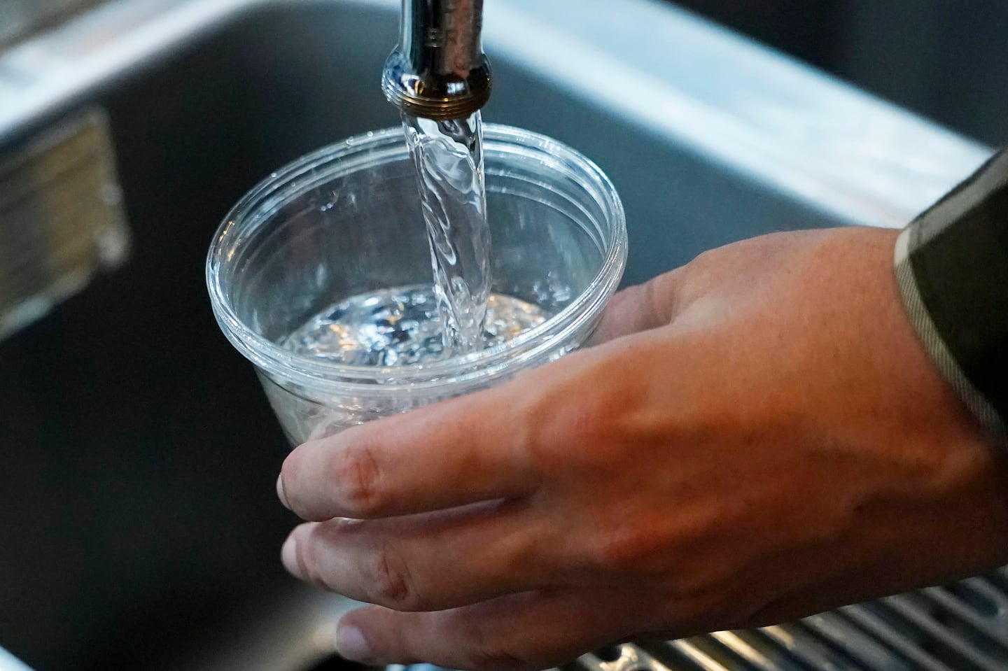 A cup of water is drawn from a faucet.