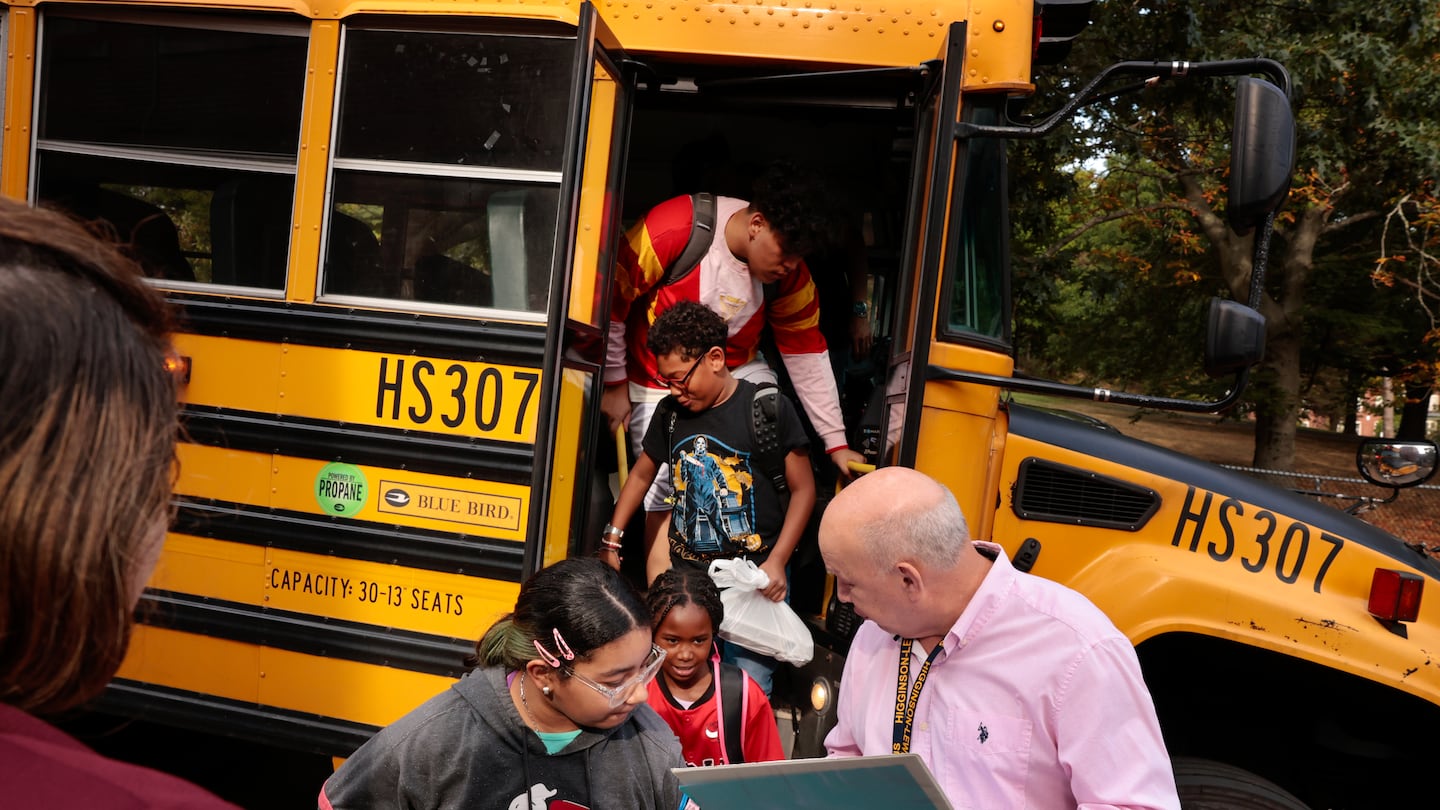 Science coach Fernando Cleves checked students in as they disembarked their bus at  Higginson-Lewis K-8 School in Boston on Sept. 18.