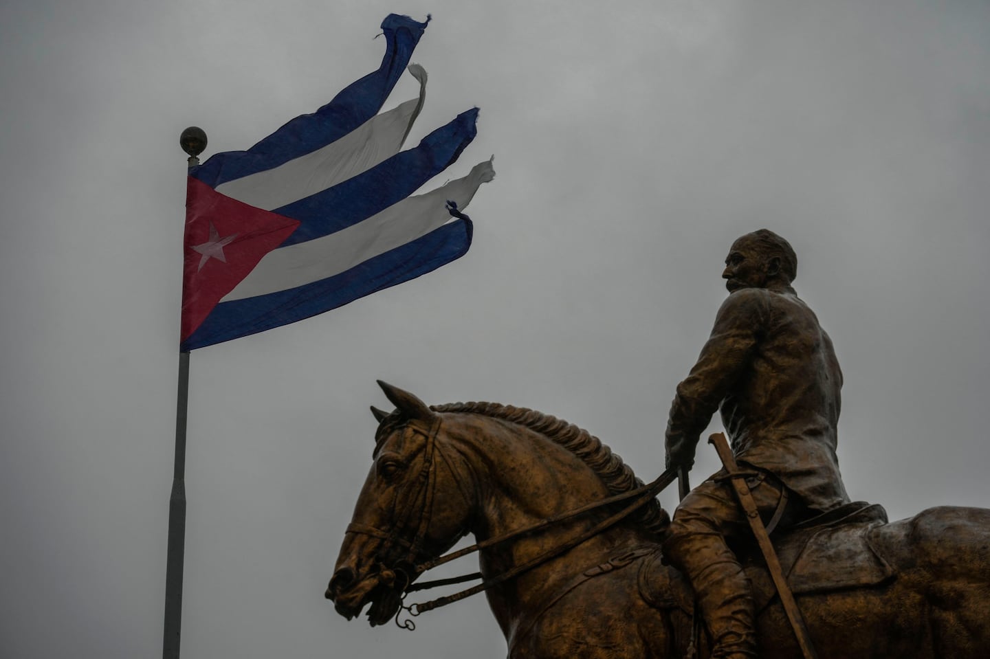 A Cuban flag shredded by the winds of Hurricane Rafael flies above the statue of General Calixto Garcia in Havana, Cuba, Wednesday, Nov. 6, 2024. 