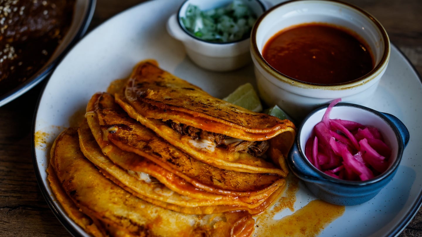 Tacos de Birria, tortillas dipped in a rich consommé and filled with beef birria and melted cheese, at Abuela's Table in Jamaica Plain.