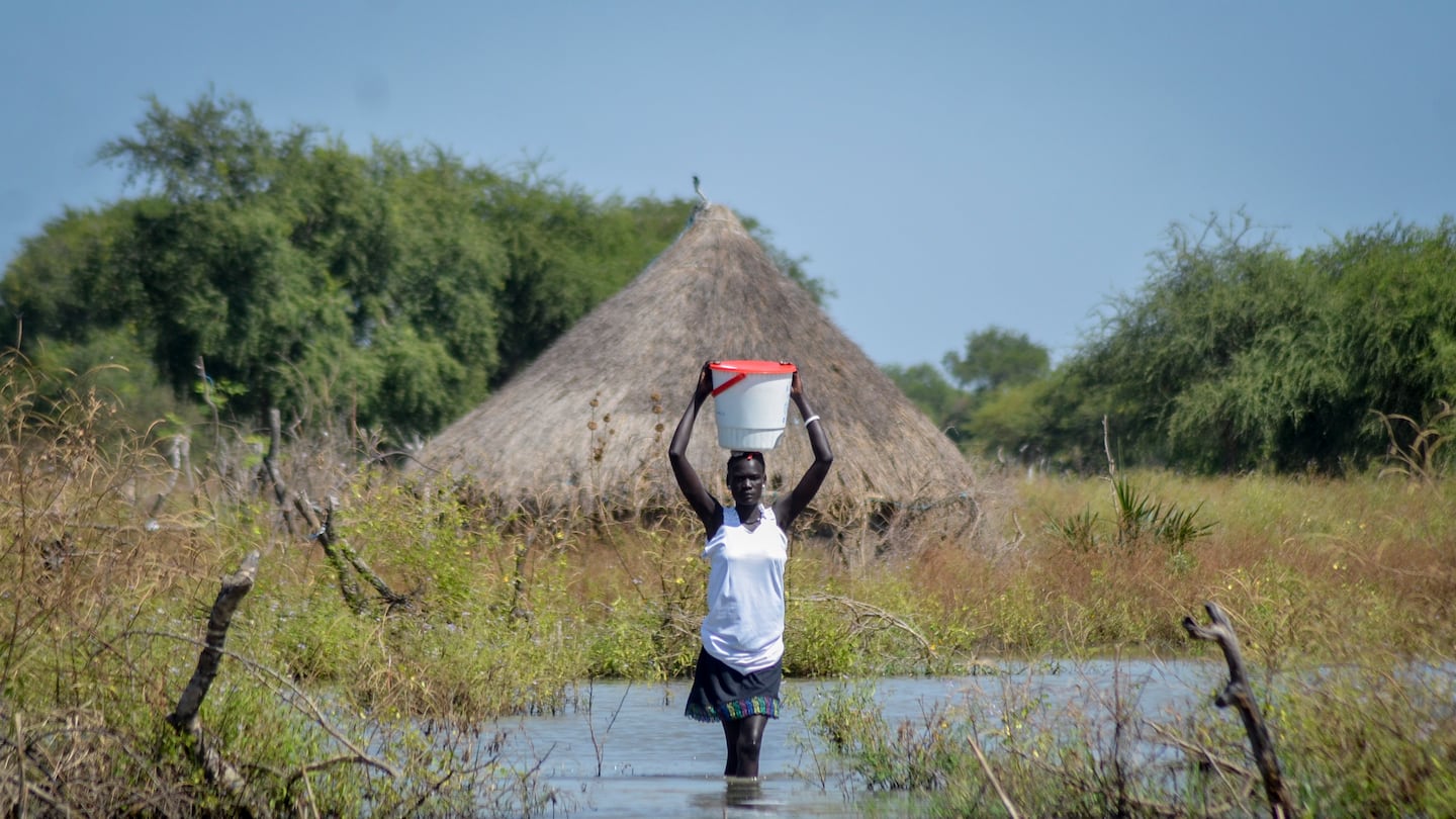 A woman carries a bucket on her head as she wades through floodwaters in the village of Wang Chot, in South Sudan, on Nov. 26, 2020.