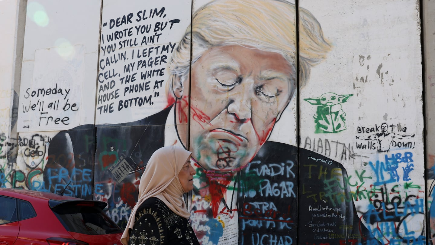 A Palestinian woman in the occupied West Bank walked past a mural depicting Donald Trump on Israel's separation wall on Tuesday.