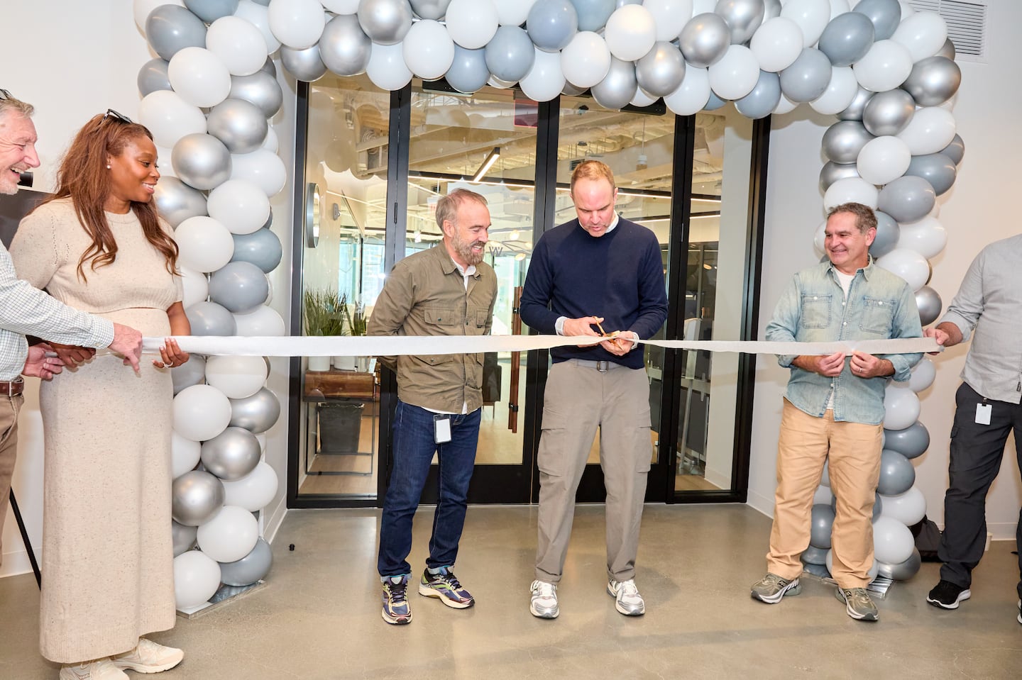 Rob Griffiths (center, left), Saucony president, and Chris Hufnagel (center, right), chief executive of Saucony parent Wolverine Worldwide, cut a ceremonial ribbon at Wolverine's new Boston office.