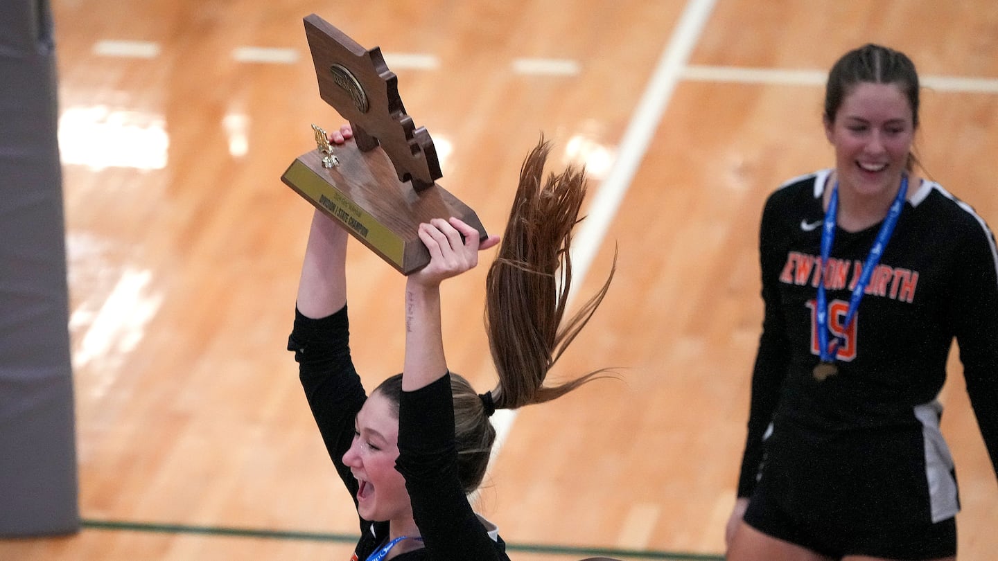 Newton North's Devon Burke (No. 8) hoists the championship trophy after the top-seeded Tigers swept second-seeded Brookline in a three-set victory in the Division 1 girls' volleyball state championship.