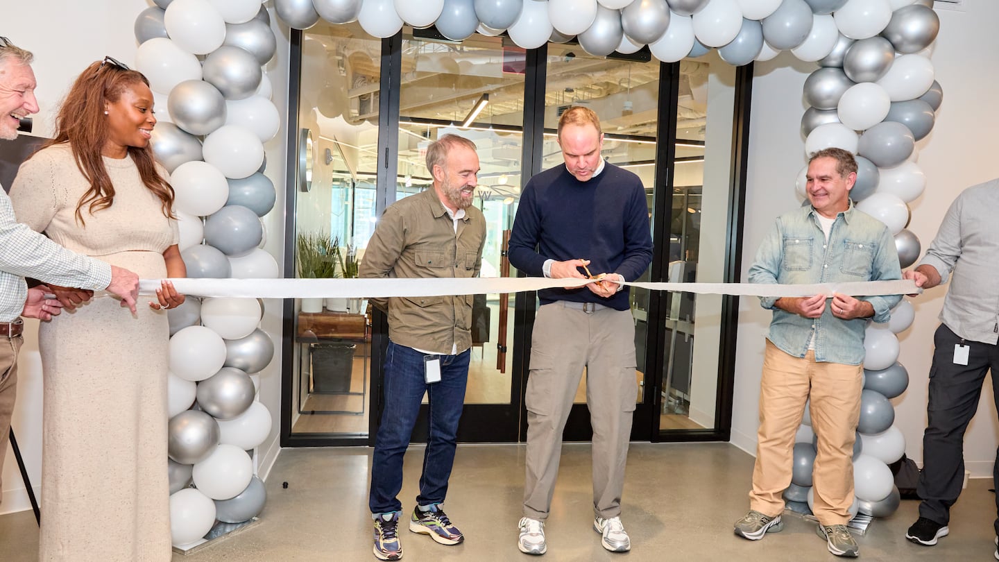 Rob Griffiths (center, left), Saucony president, and Chris Hufnagel (center, right), chief executive of Saucony parent Wolverine Worldwide, cut a ceremonial ribbon at Wolverine's new Boston office.