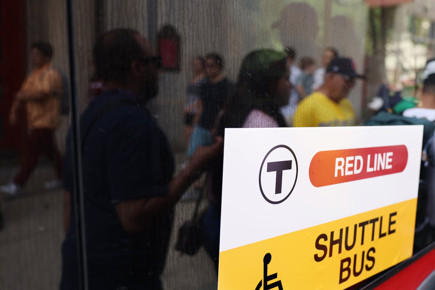 Passengers were reflected in a window as they boarded a shuttle bus to Alewife after Red Line service was disrupted.