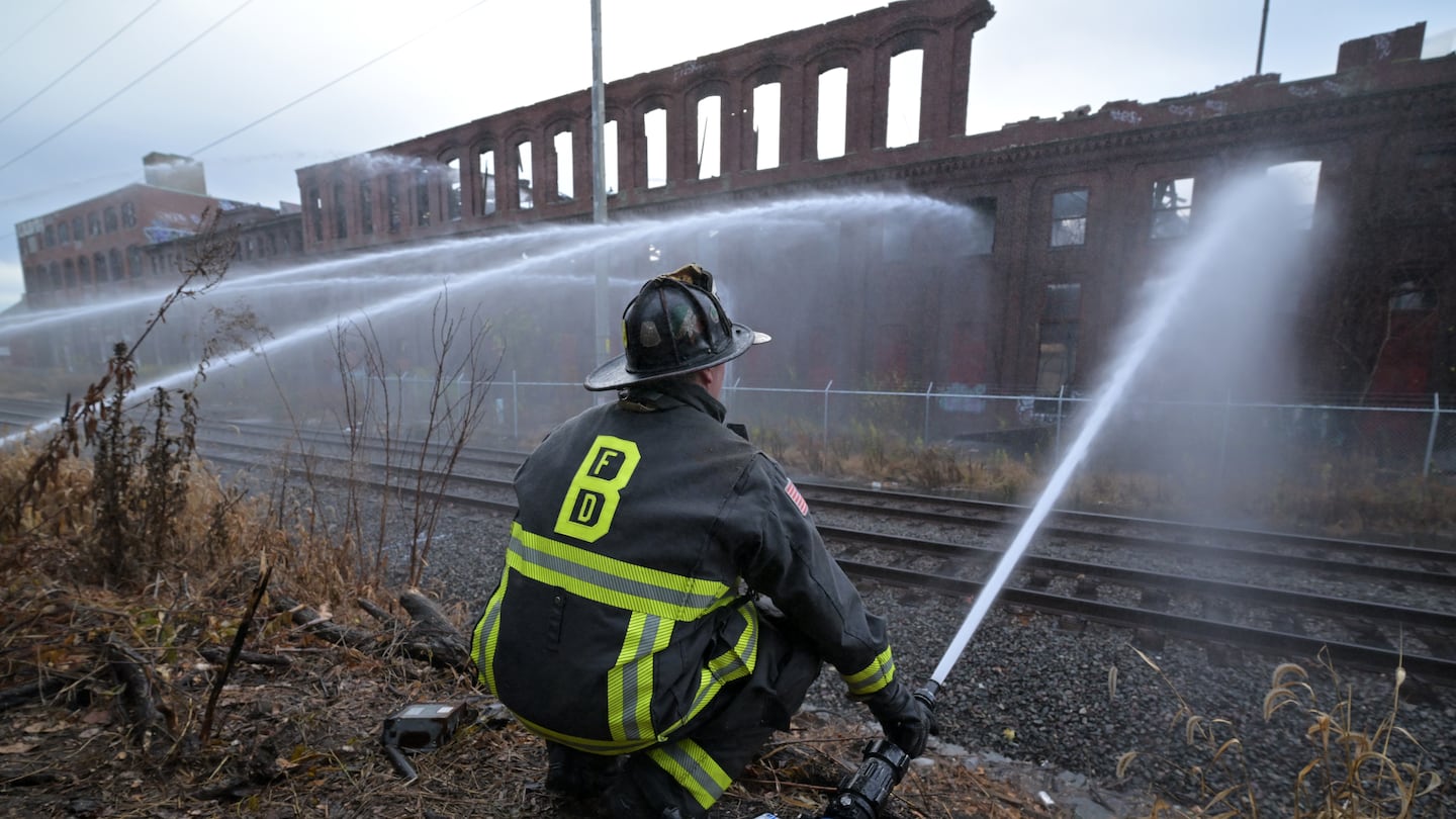 Firefighters hosed down a multi-alarm fire in a long abandoned industrial park in Chelsea, which shut down Commuter Rail service on adjacent tracks, and forced the closure of several nearby schools.