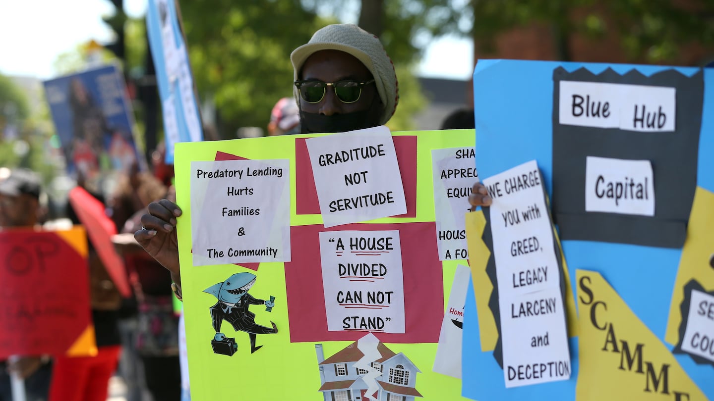 NACA, the nation’s largest nonprofit homeownership organization, lead a group of homeowners including David Walker, with sign, in a protest against BlueHub Capital's SUN program.