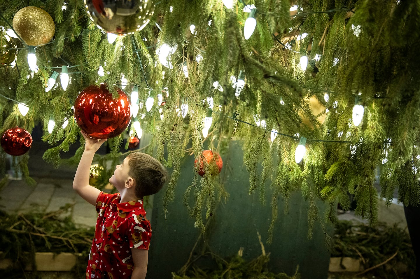 A child admires himself in the reflection of a Christmas ball hung from a tree outside of Faneuil Hall Marketplace during the lighting ceremony. It was the first time that they have had the ceremony since 2019. 

STANDALONE