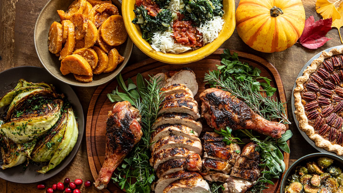 A contemporary Thanksgiving feast includes (clockwise from bottom left): Pan-Braised Cabbage with Herbs, Miso-Maple Butternut, Spinach-Rice Pilaf, Salted Caramel Pecan Pie, Parmesan Brussels Sprouts, Roast Turkey with Spice Rub.