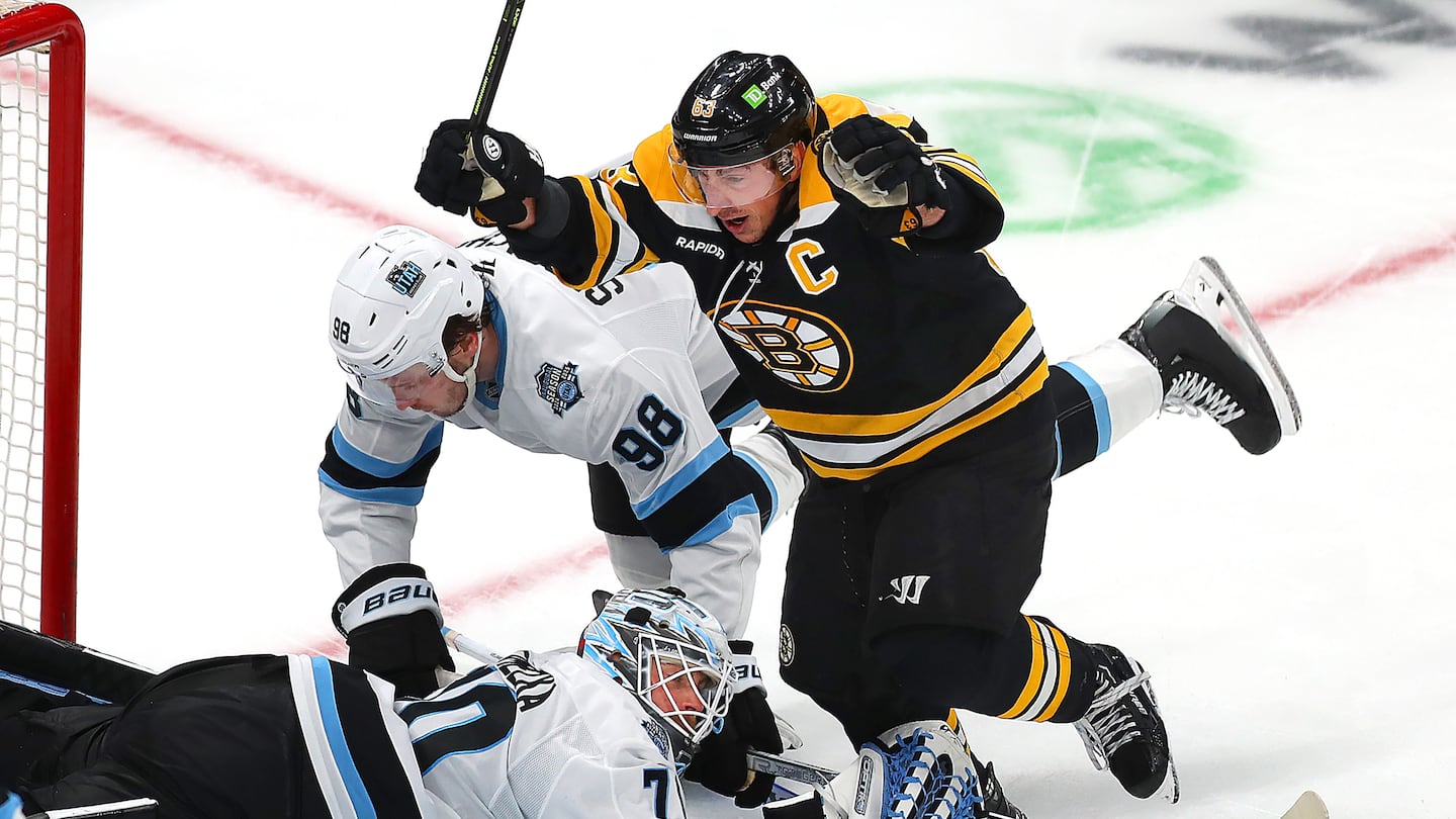 Bruins captain Brad Marchand (63) celebrates the second period power-play goal by Elias Lindholm while Utah goalie Karel Vejmelka lies down and out.