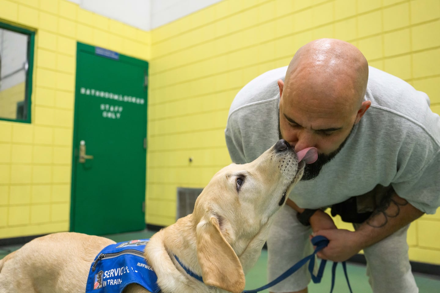 Derick Kaplinger, who is incarcerated, is licked by service dog trainee Sumner.