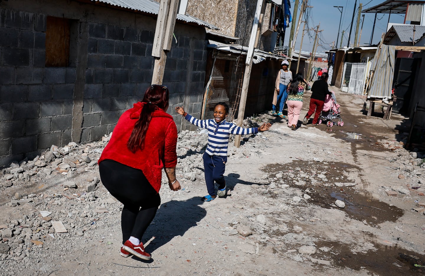 Inés Fuentes Arenas, a Chilean community leader, reached out to embrace a young boy in the "Nuevo Amanecer" encampment, located in the Cerrillos district of Santiago, Chile.