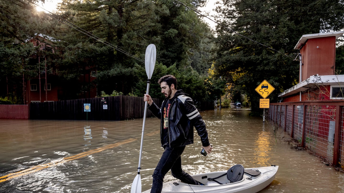 Tristan Millstone steps in water after kayaking across a flooded section of Neely Road to buy groceries following a major storm in Guerneville, Cali., on Nov. 23.