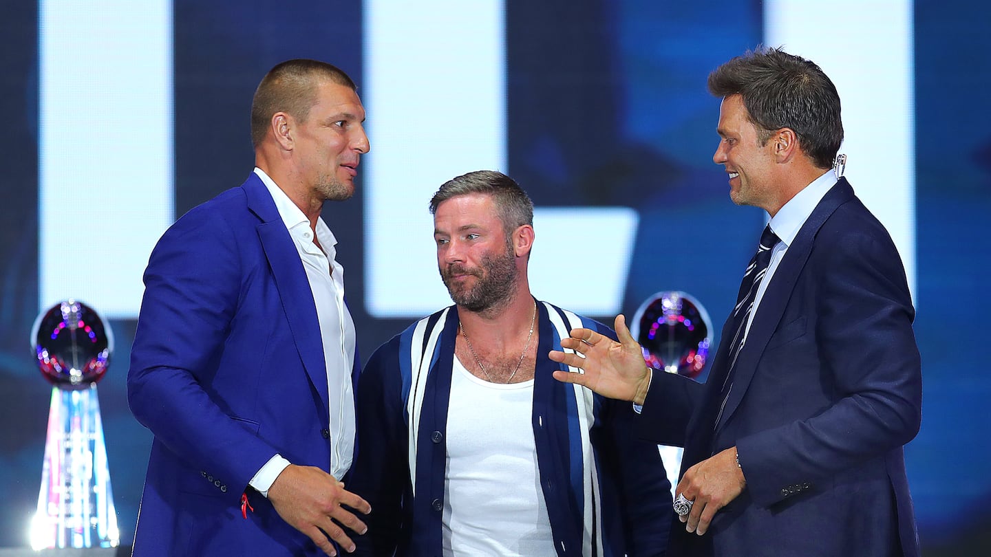 Rob Gronkowski (left) and Julian Edelman greet Tom Brady as the former New England Patriots quarterback was inducted into the Patriots Hall of Fame at a June 12, 2024 ceremony at Gillette Stadium.