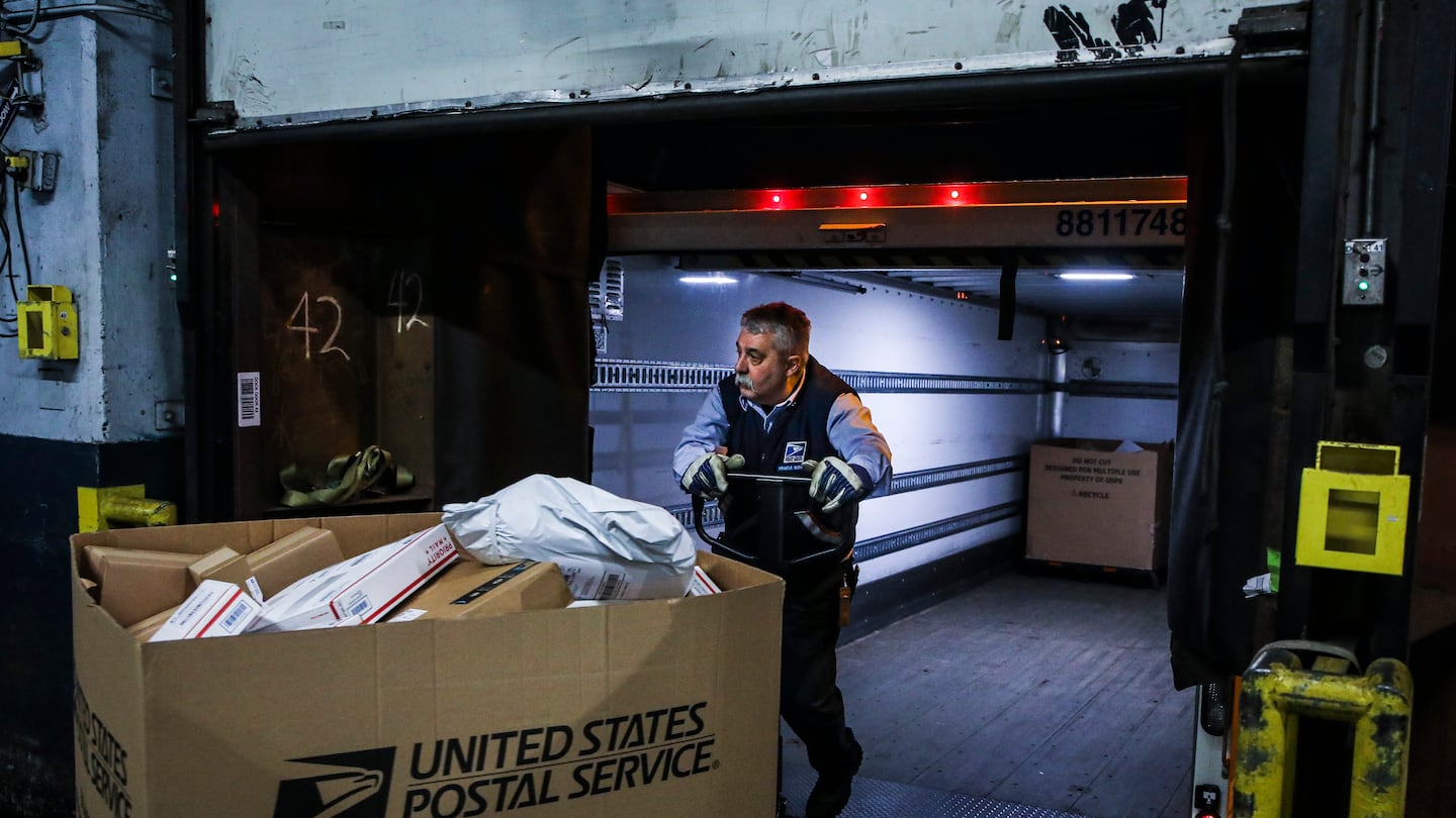 A US Postal Service driver loads trucks with mail to be sent out to various locations in Boston from the Fort Point United States Postal Service processing facility on Dec. 16, 2021.