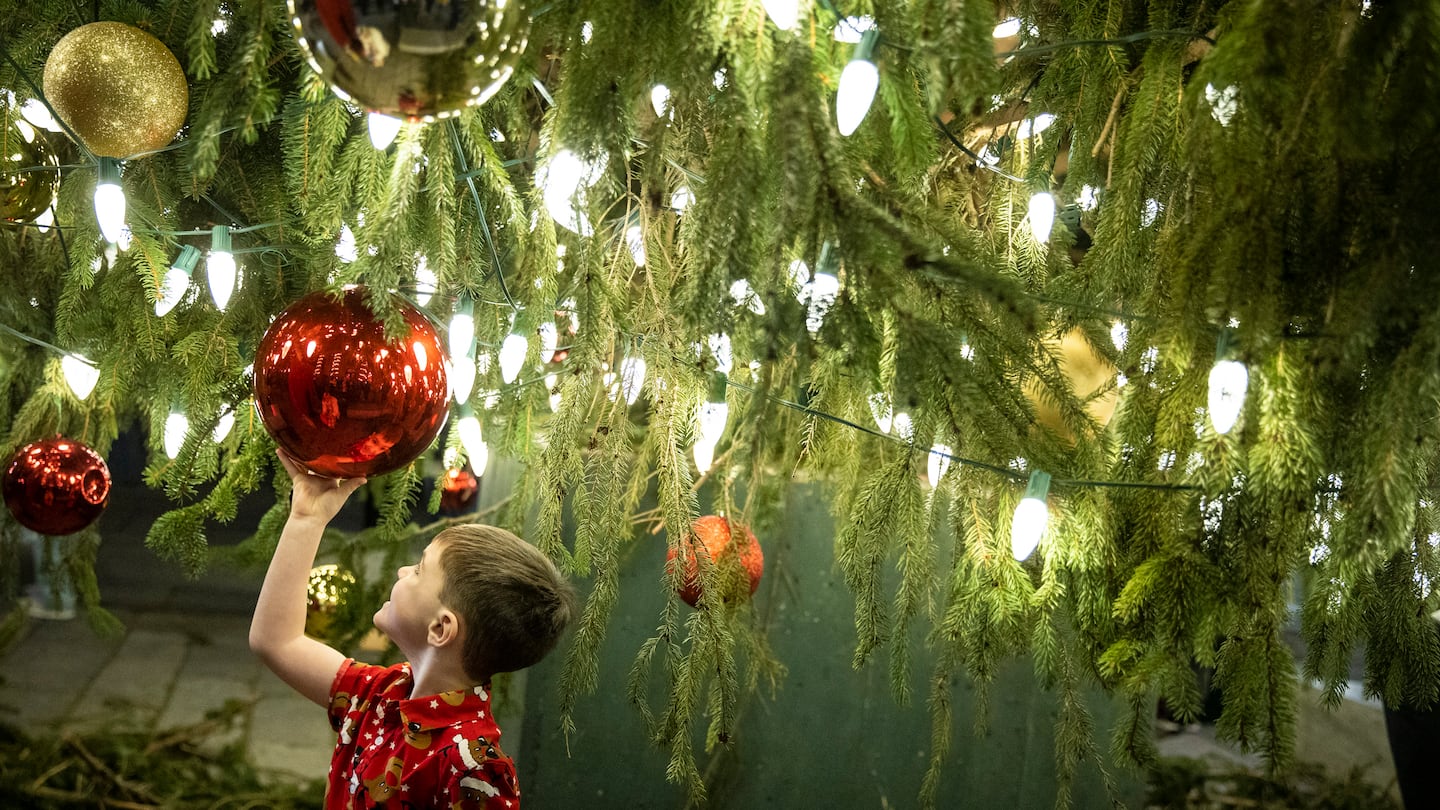 A child admires himself in the reflection of a Christmas ball hung from a tree outside of Faneuil Hall Marketplace during the lighting ceremony. It was the first time that they have had the ceremony since 2019. 

STANDALONE