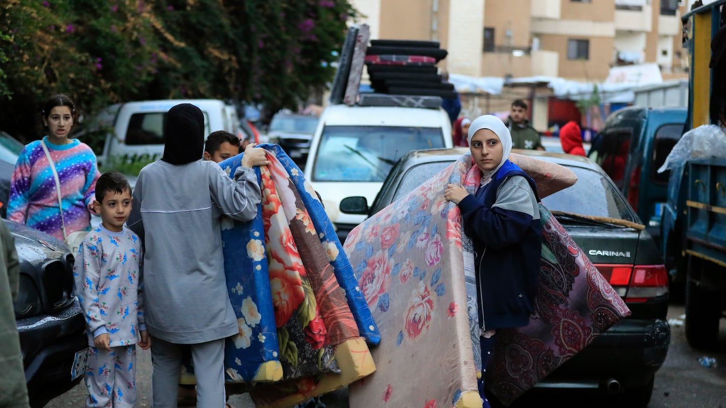 Displaced families carry mattresses as they prepare to return to their villages after a ceasefire between Israel and Hezbollah went into effect in Sidon, Lebanon, Wednesday, Nov. 27, 2024.