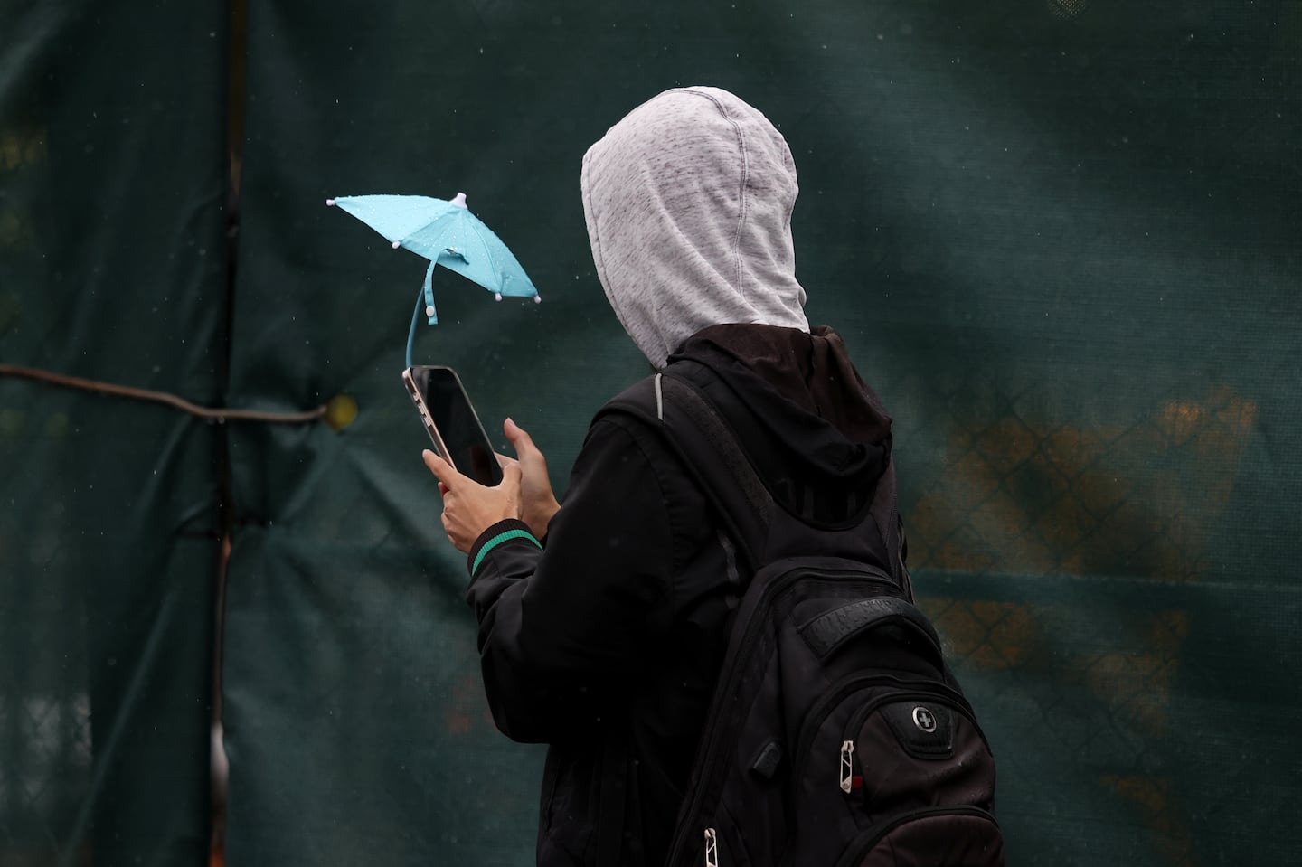 A pedestrian had an umbrella for his phone but not himself as rain fell in Boston.