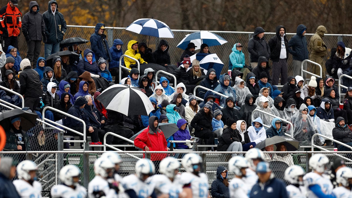 Fans use umbrellas to shield from the rain during the Thanksgiving Day game between Franklin and King Philip.