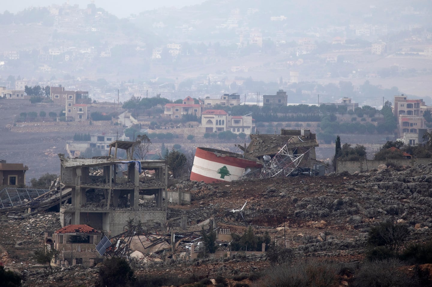 NORTHERN ISRAEL, ISRAEL - NOVEMBER 27: The flag of Lebanon is painted on a destroyed structure in the village of Weiss El Jabal as seen from a position on the Israeli side of the border in Northern Israel on November 27, 2024.