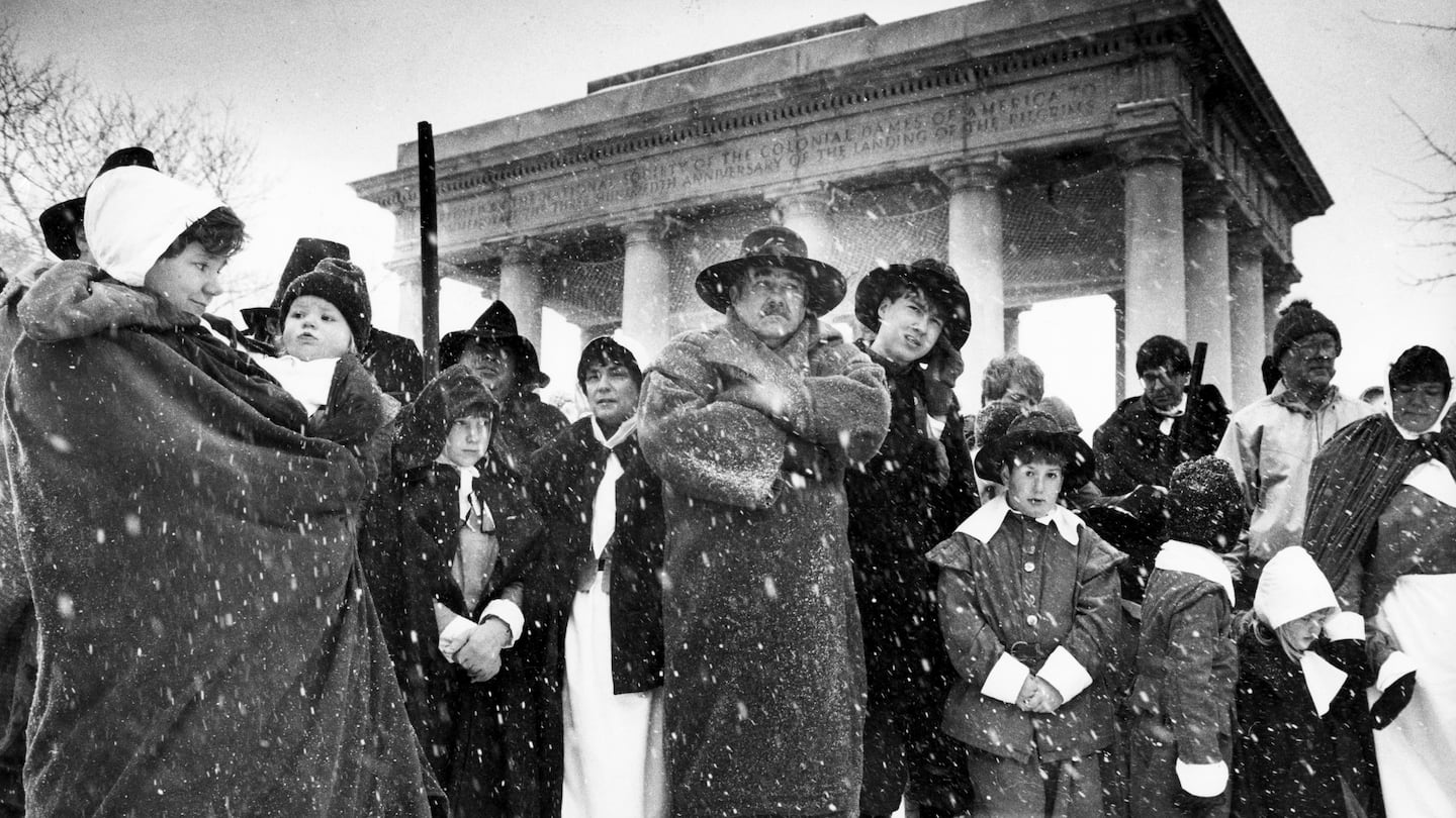 Imelda Goedecke, left, holds her daughter Micah, 14 months, as they pause with others in front of the columned canopy over Plymouth Rock for a prayer service during the annual Thanksgiving Day Pilgrims' Progress on Nov. 23, 1989, the day New England saw what forecasters called the biggest Thanksgiving snowstorm since 1925.