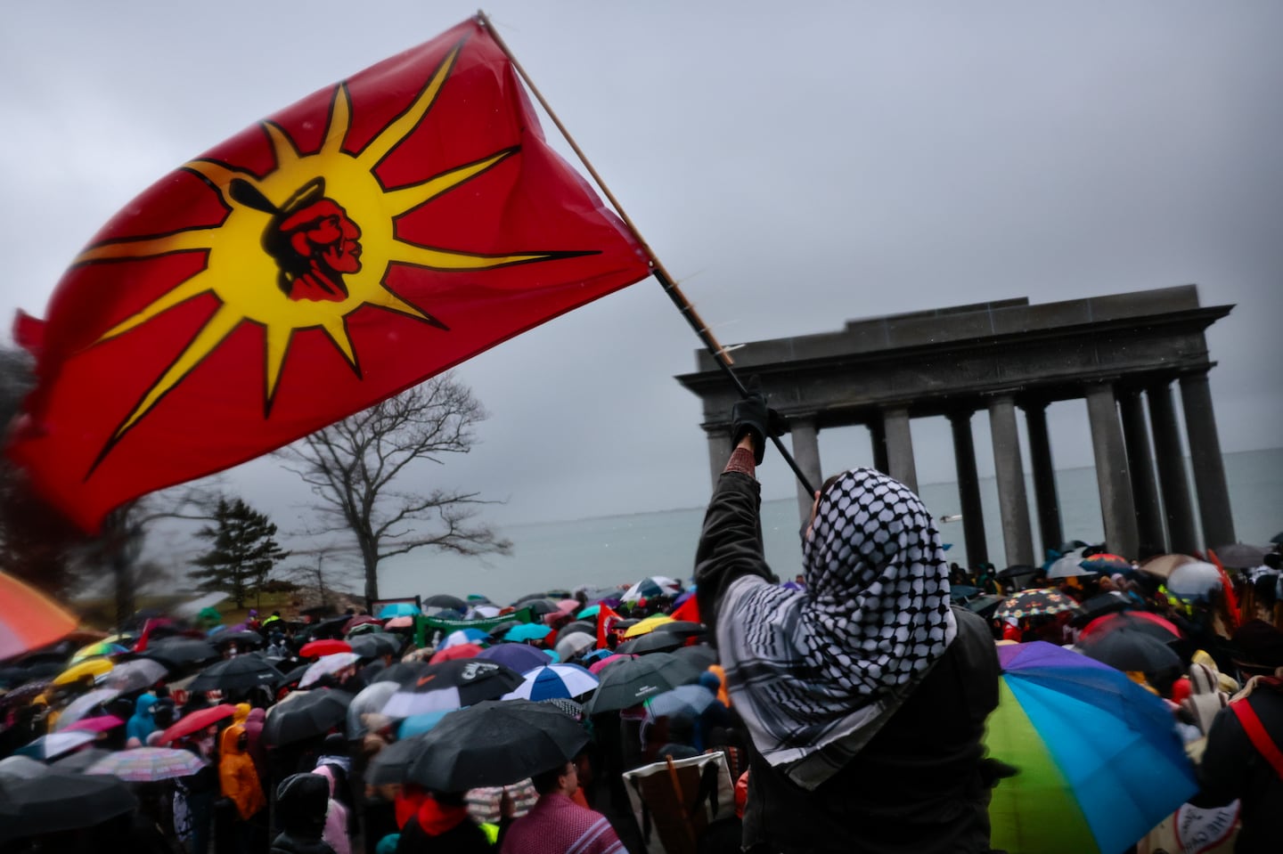 A demonstrator raised a flag as marchers gathered at Plymouth Rock during the 55th National Day of Mourning on Cole's Hill in Plymouth.