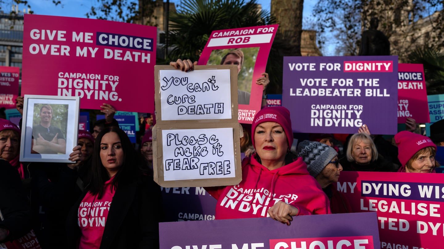 Campaigners hold placards as they protest in support of assisted dying on Nov. 29 in London, England.