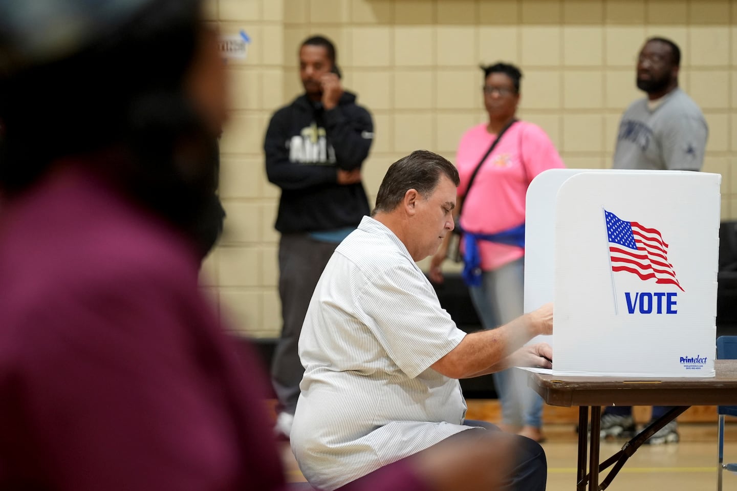 A voter casts his ballot while others wait in line for their opportunity to vote on Nov. 5, 2024, in a Jackson, Miss., precinct.