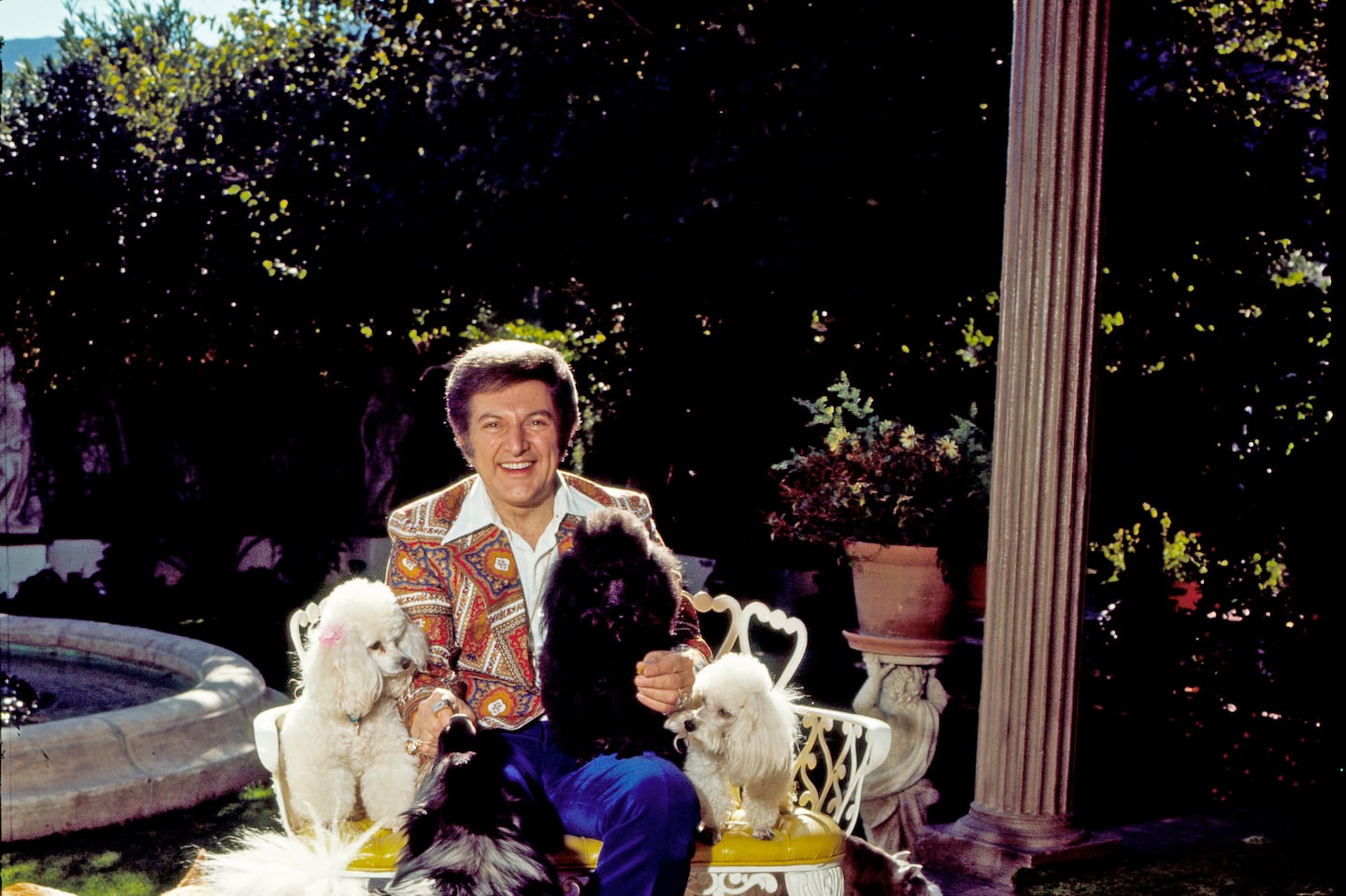 Pianist, singer and actor Liberace sitting on his patio at his Palm Springs home surrounded by his dogs In September 1980. - (Eddie Sanderson/Getty Images).