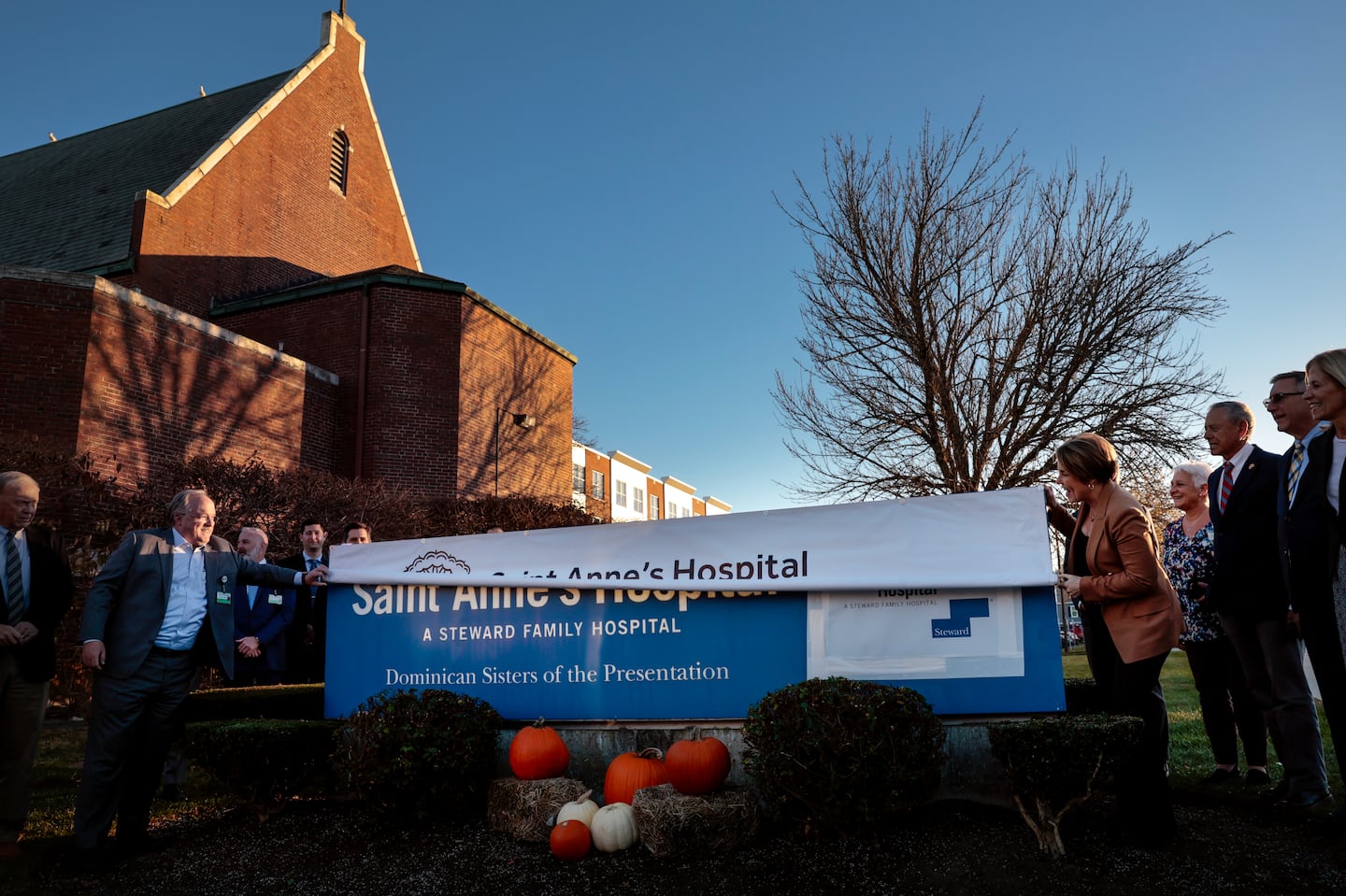 Brown University Health CEO John Fernandez (left), and Massachusetts Governor Maura Healey unfurled a Brown University Health banner for St. Anne's Hospital, covering the former Steward Family Hospital sign, during a ceremony at the Fall River hospital on Nov. 19.