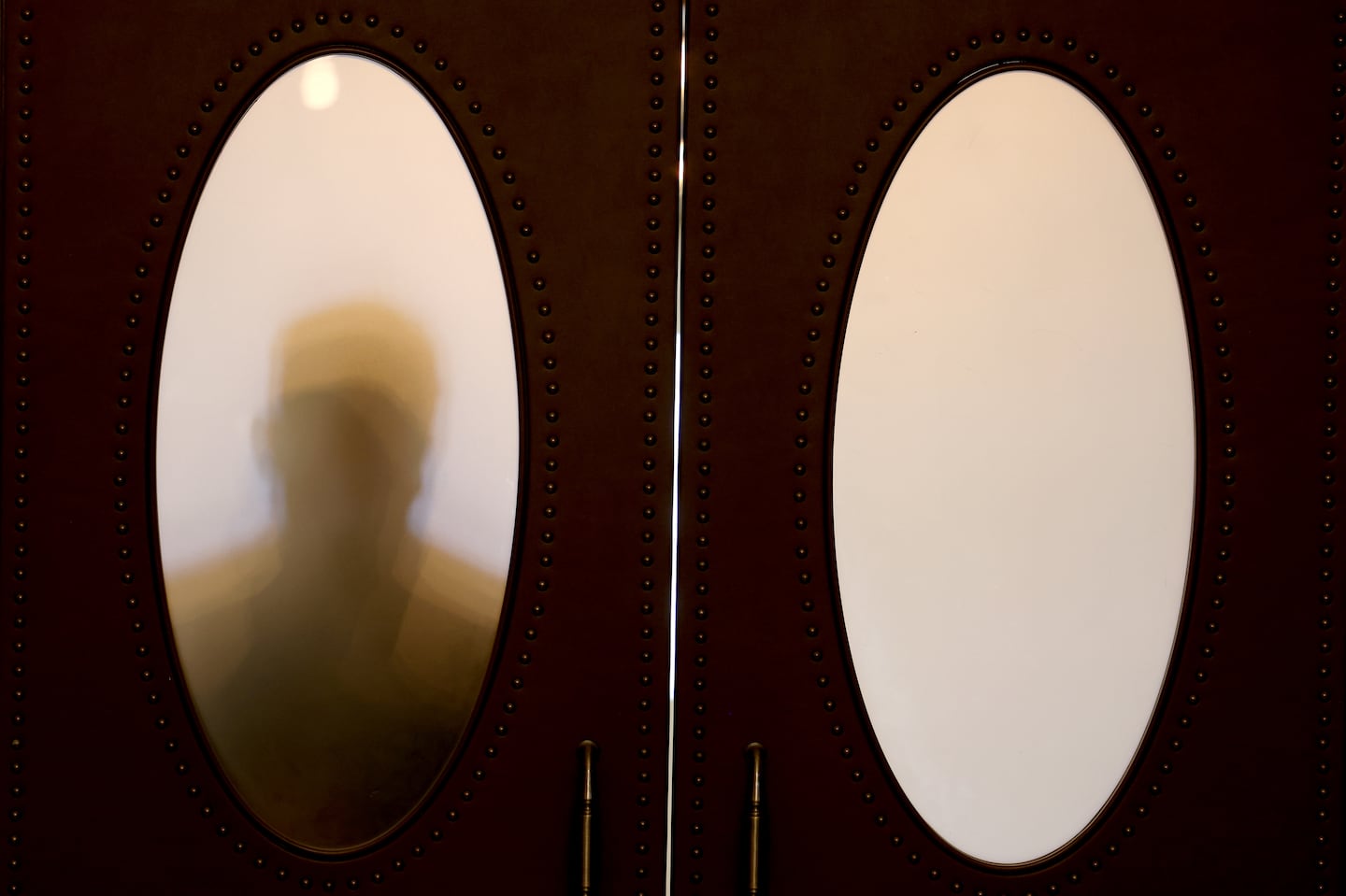 A Senate aide was silhouetted against the door leading to the Senate chambers on what was scheduled to be the final day of the Legislature's formal sessions in July.