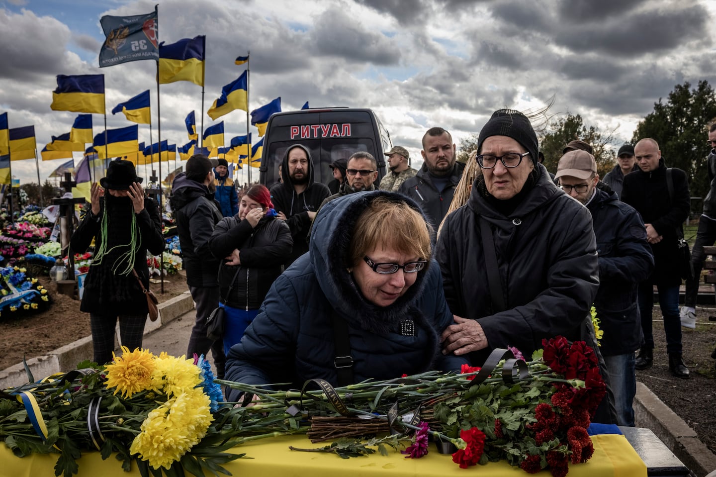 Women mourn a fallen Ukrainian soldier at a cemetery on the outskirts of Kherson last year. MUST CREDIT: Ed Ram for The Washington Post