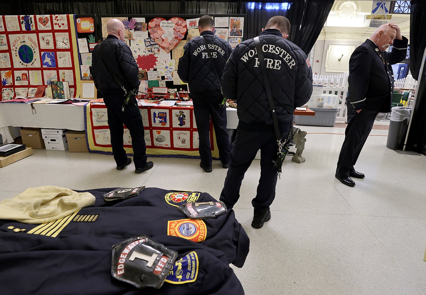 Current and retired firefighters look at items on display at a pop-up exhibit at Union Station. The display tells the story of the Worcester Cold Storage and Warehouse fire.