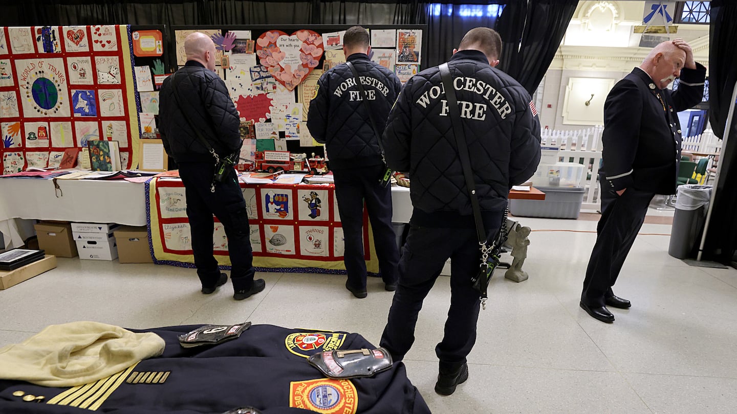 Current and retired firefighters look at items on display at a pop-up exhibit at Union Station. The display tells the story of the Worcester Cold Storage and Warehouse fire.