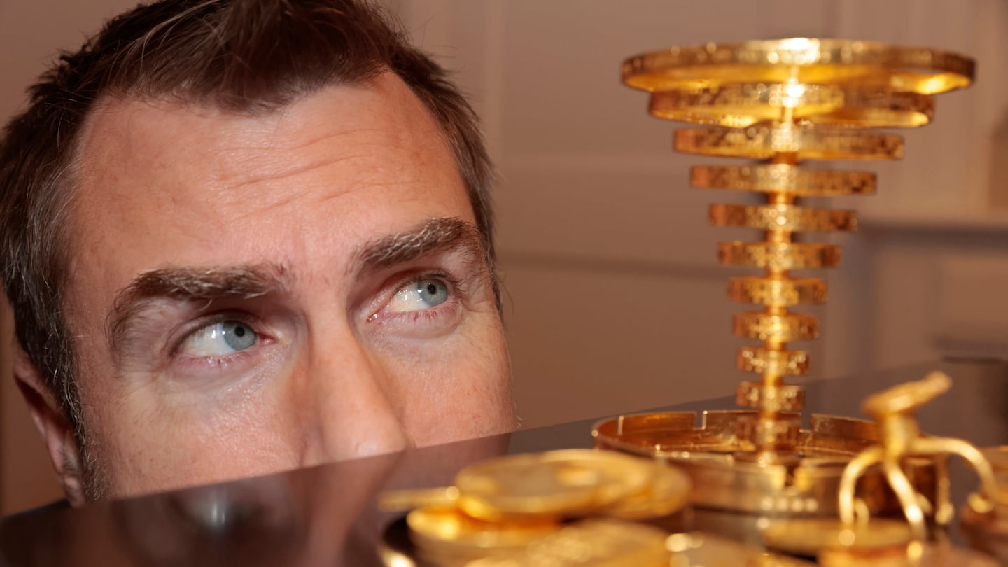 Meteorologist Dan Leonard posed with the golden trophy he located in the woods during the initial Project Skydrop treasure hunt and the $87,600 prize in gold coins.