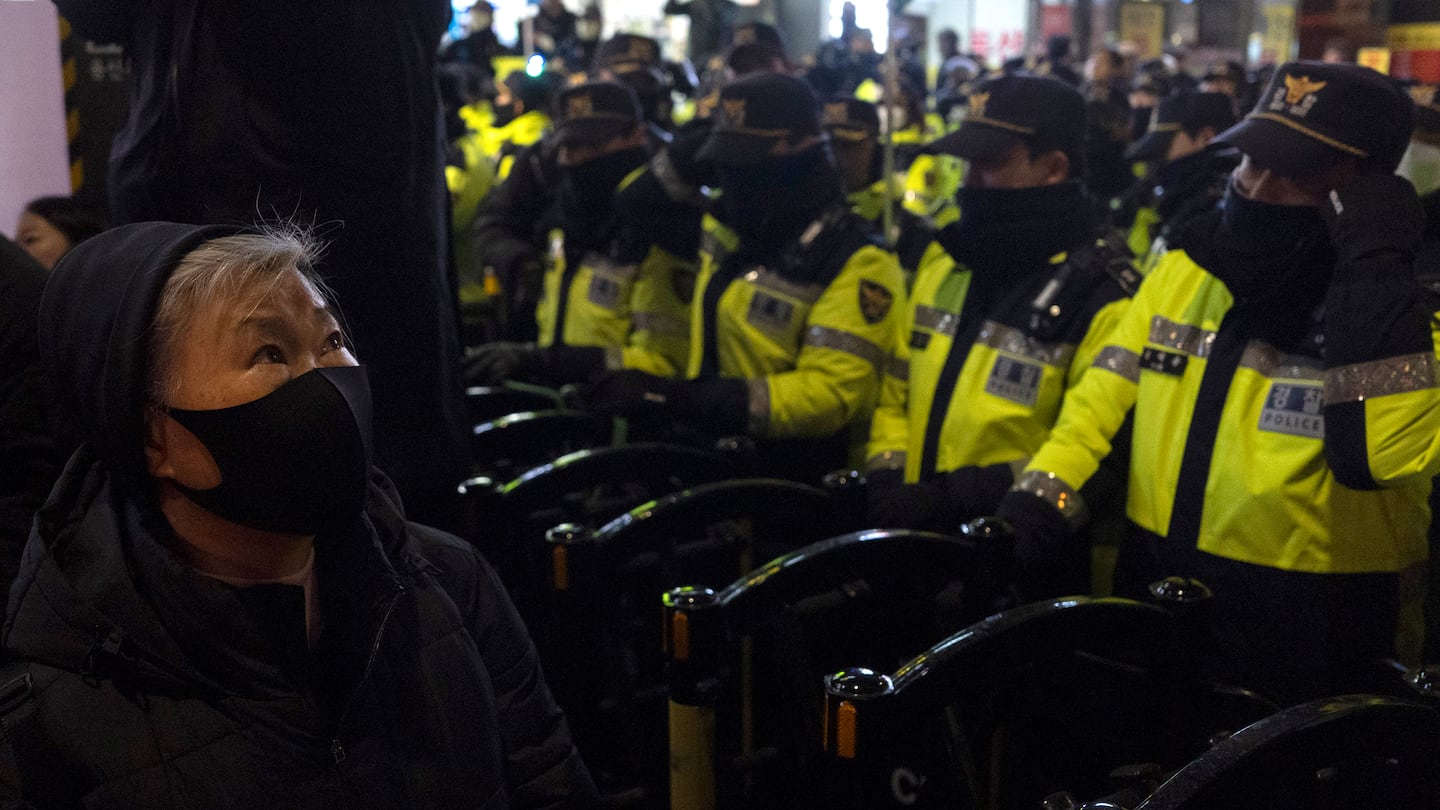 A woman looks up near a police barricade with rows of police officers blocking a protest march to the presidential office after a candlelight vigil against South Korean President Yoon Suk Yeol, in Seoul, South Korea, on Dec. 4.