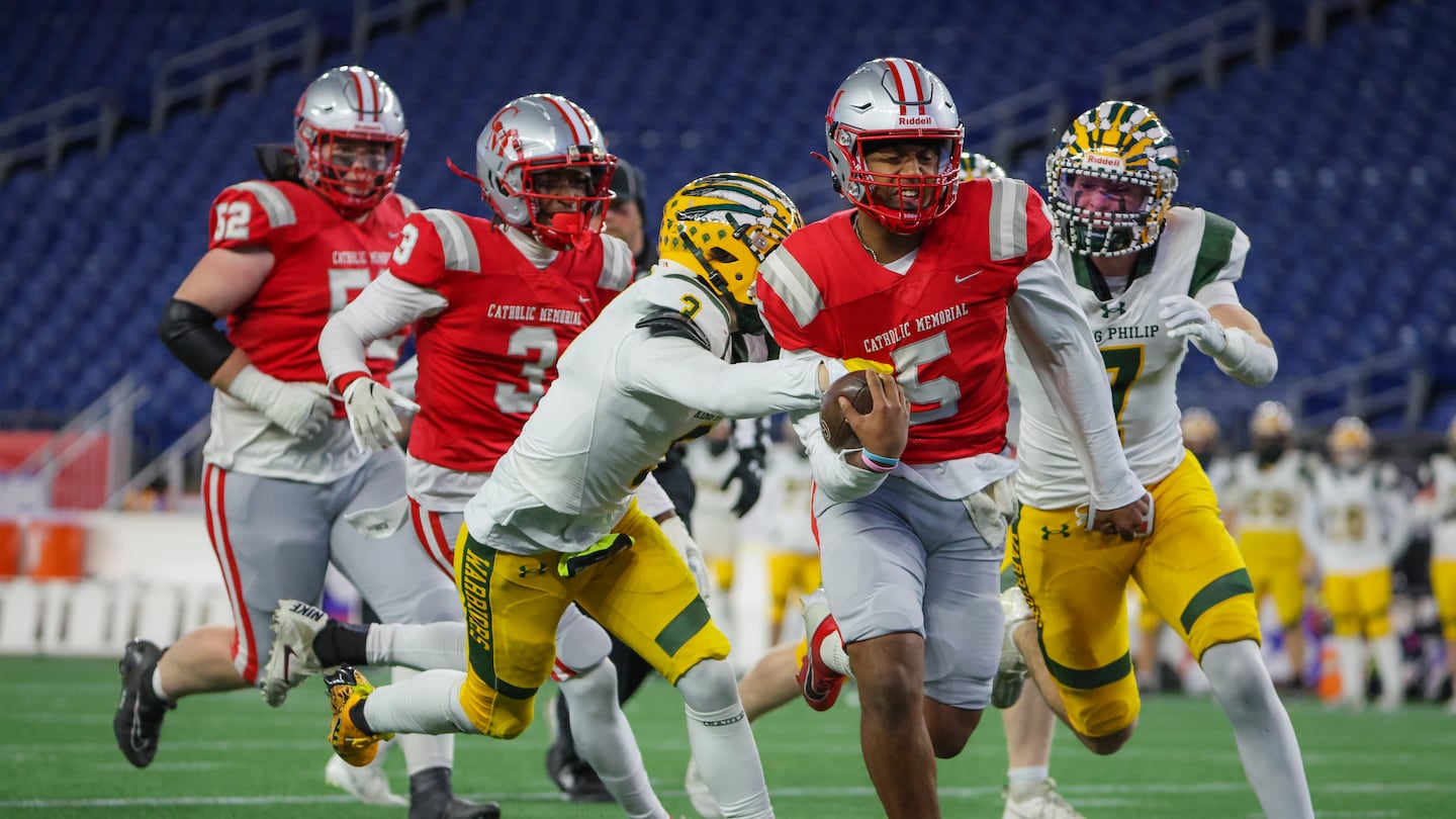 Catholic Memorial quarterback Kise Flannery runs up the middle under pressure from King Philip's Hayden Schmitz.