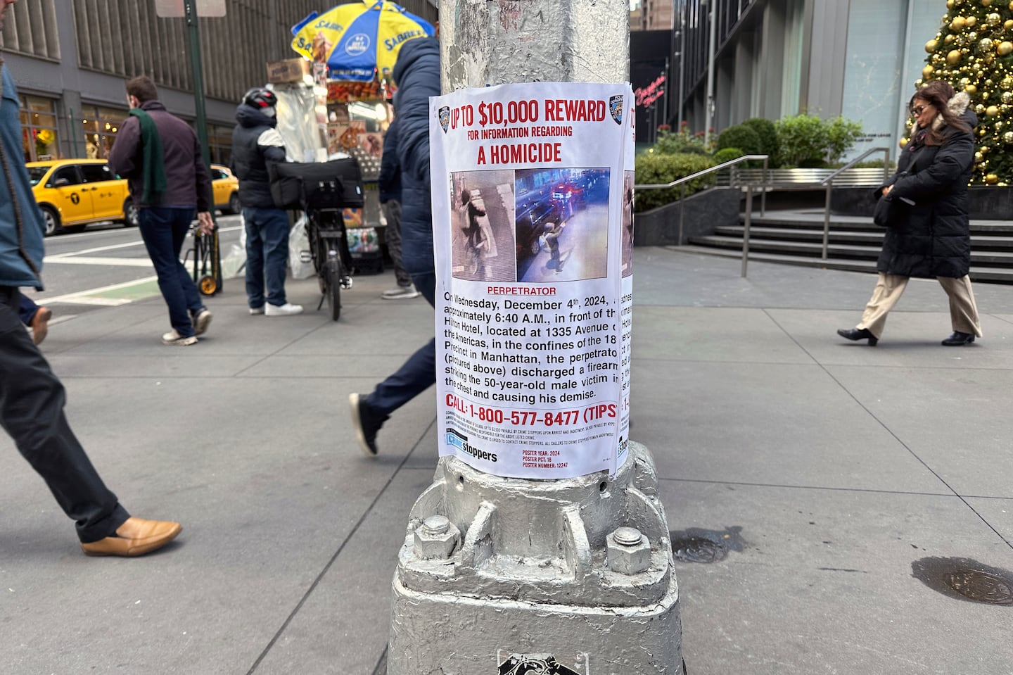 A reward poster hangs on a light pole outside the New York Hilton Midtown Hotel in New York on Thursday where Brian Thompson, the CEO of UnitedHealthcare, was fatally shot.