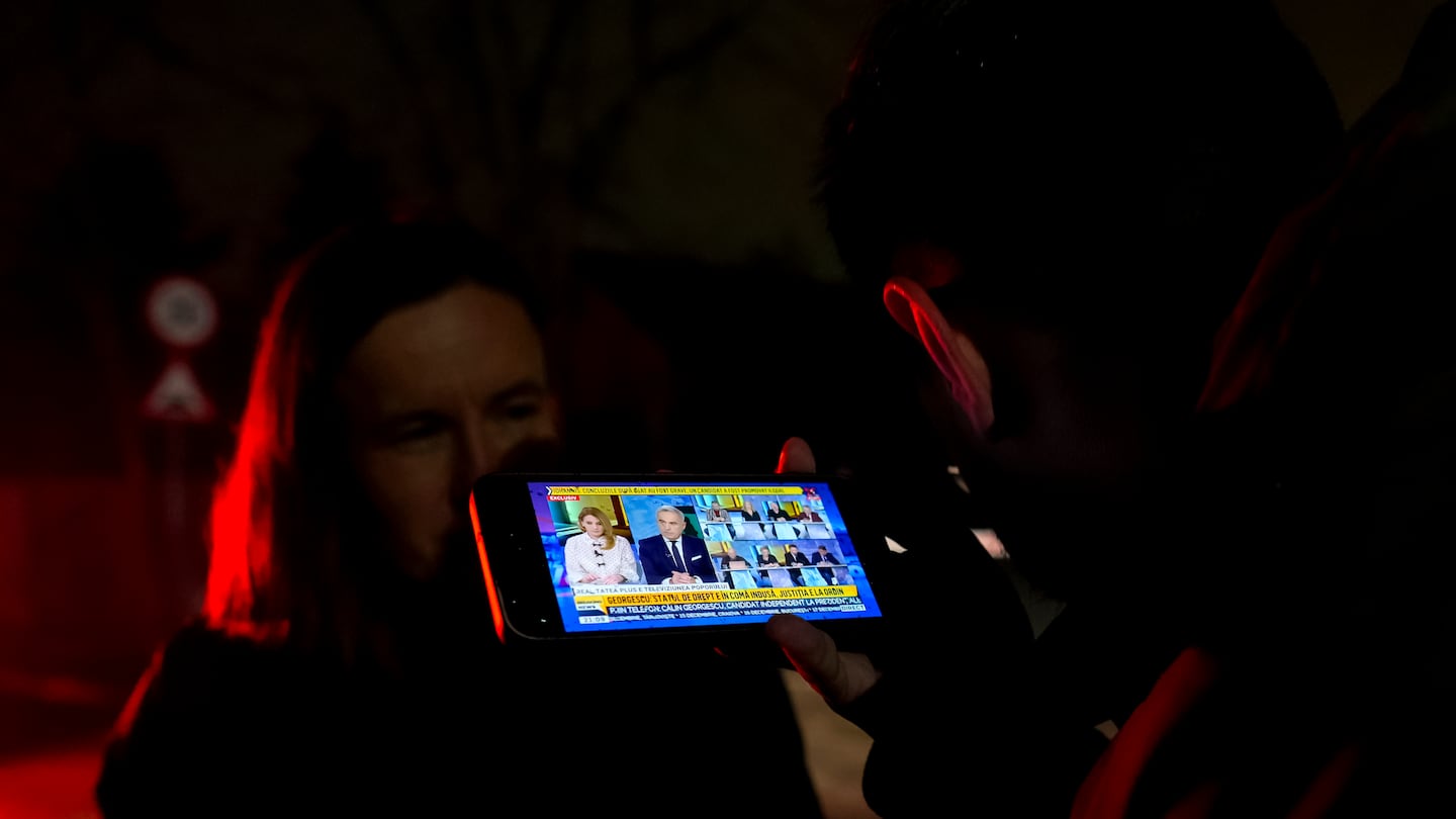 A journalist listened on his mobile phone to a live interview of Calin Georgescu, the independent candidate for presidency who won the first round of presidential elections, on a local TV channel.