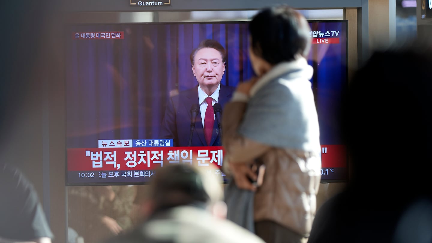 People watch a TV screen showing the live broadcast of South Korean President Yoon Suk Yeol's announcement at the Seoul Railway Station in Seoul, South Korea, Saturday, Dec. 7, 2024.