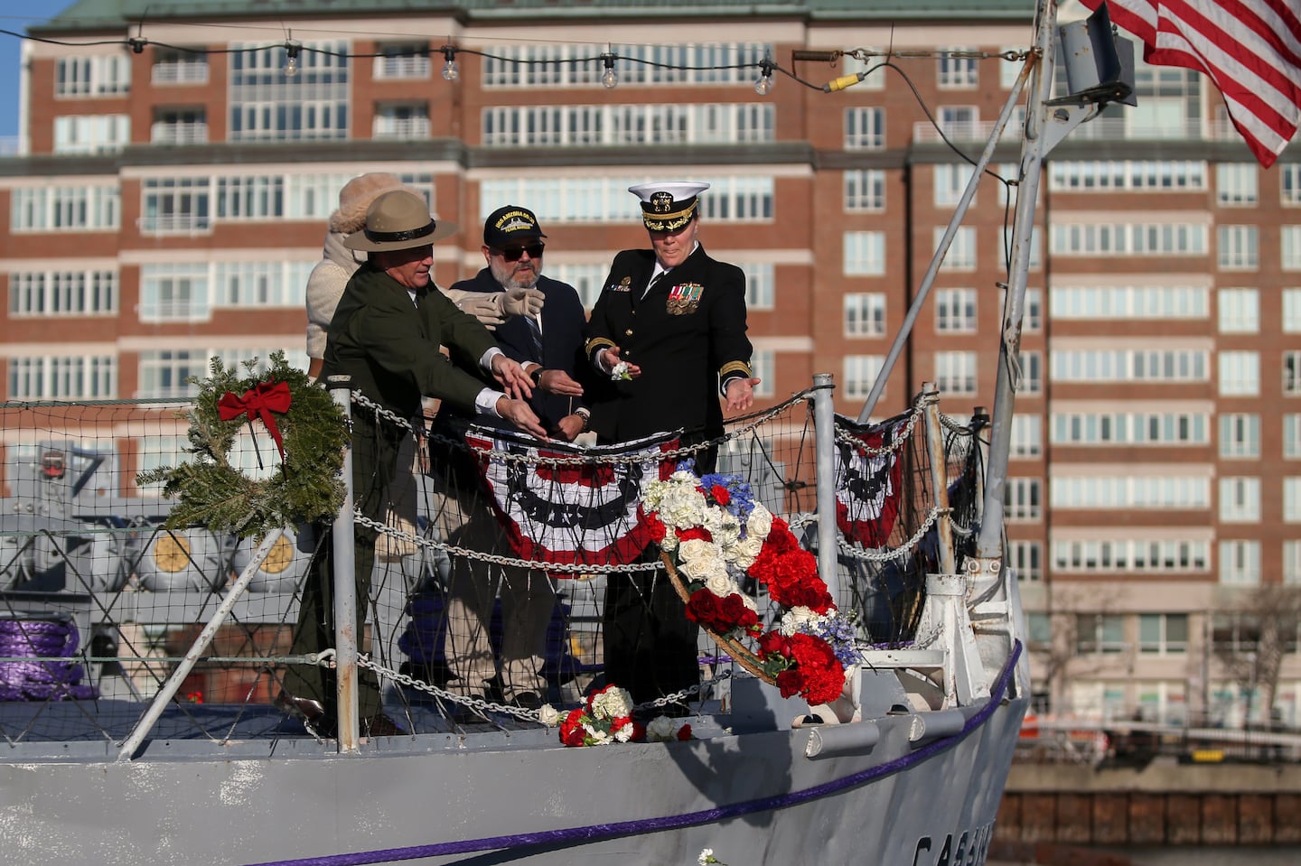 National Parks of Boston Superintendent Michael Creasey (left), Deputy Secretary of Veterans Affairs Andrea Gayle -Bennett, and other officials laid a wreath on Boston Harbor from the deck of the USS Cassin Young.