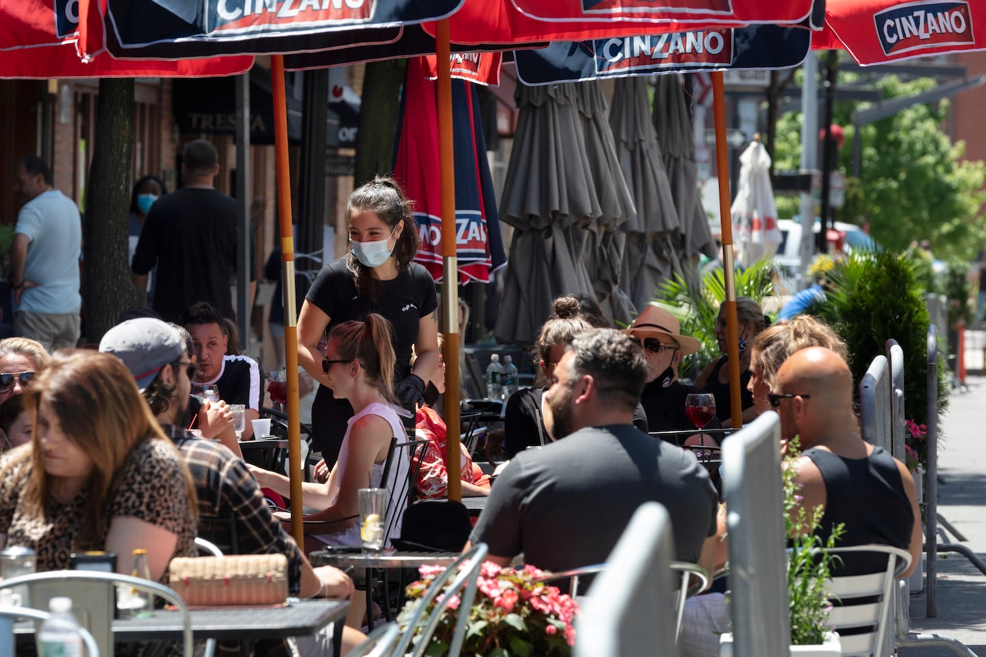 People gather at cafe tables placed in the closed parking lane on Hanover Street in the North End in June in 2020.