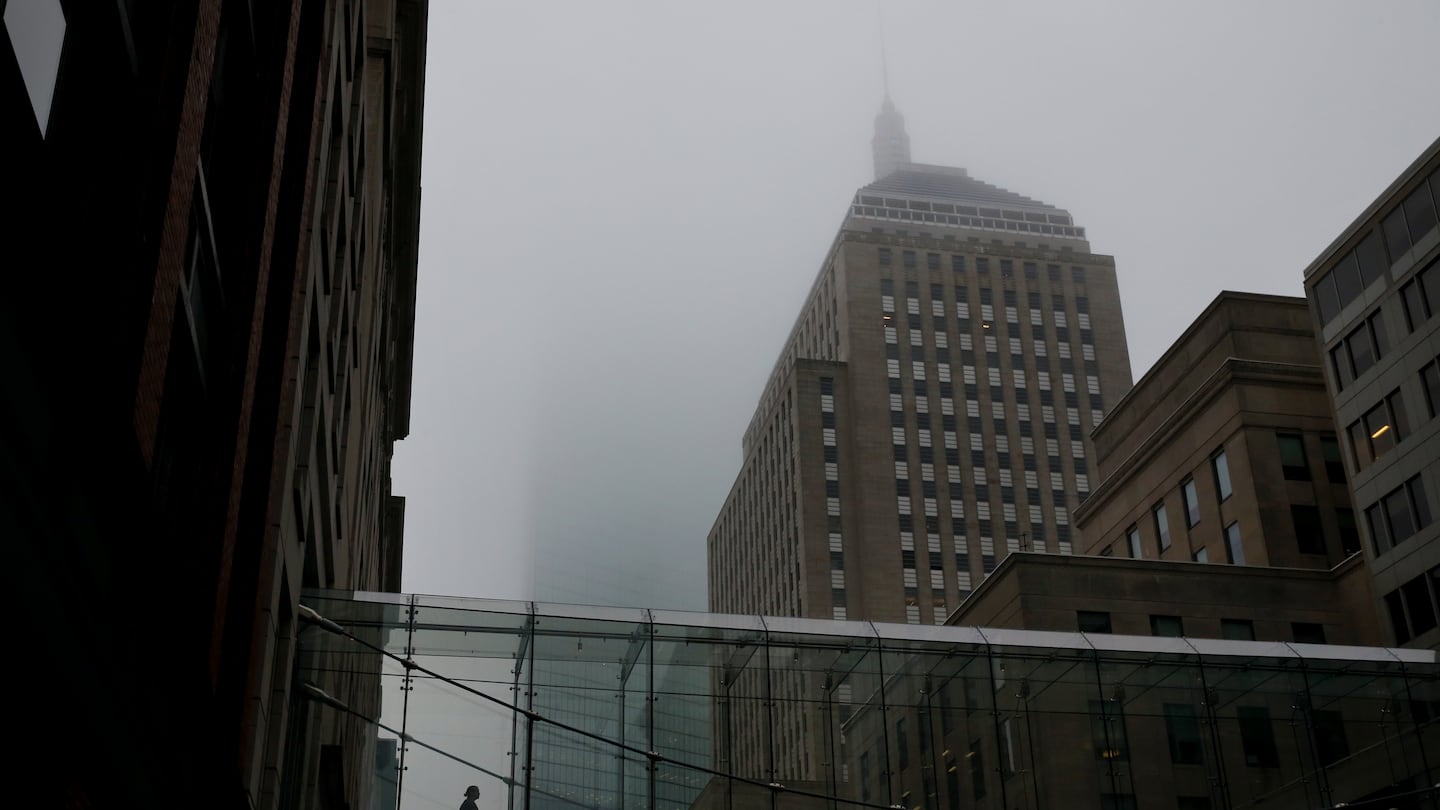 A woman uses a pedestrian bridge as fog rests over Stuart Street in Boston.